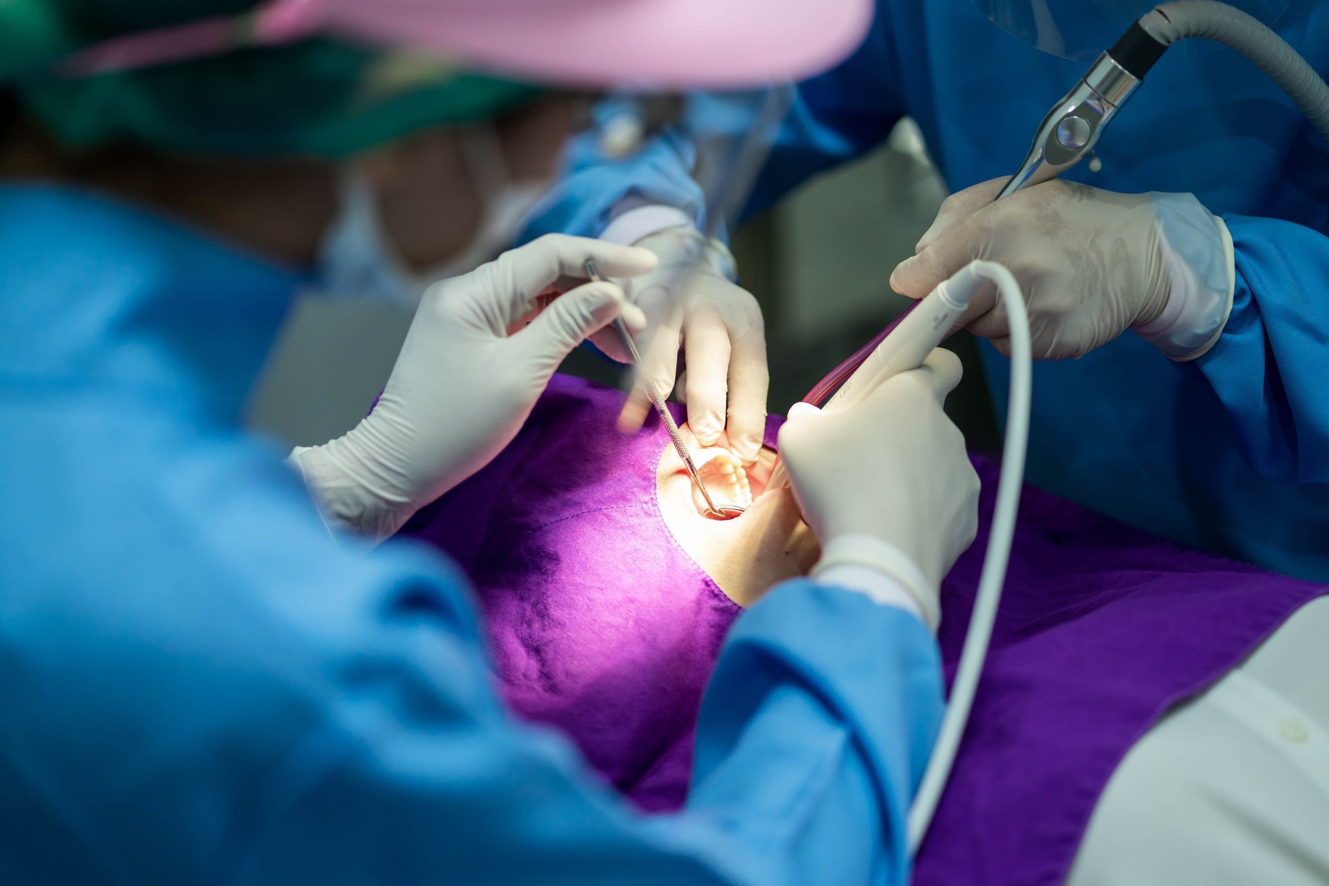 Dentist team performing a procedure on a patient under bright purple surgical drapes