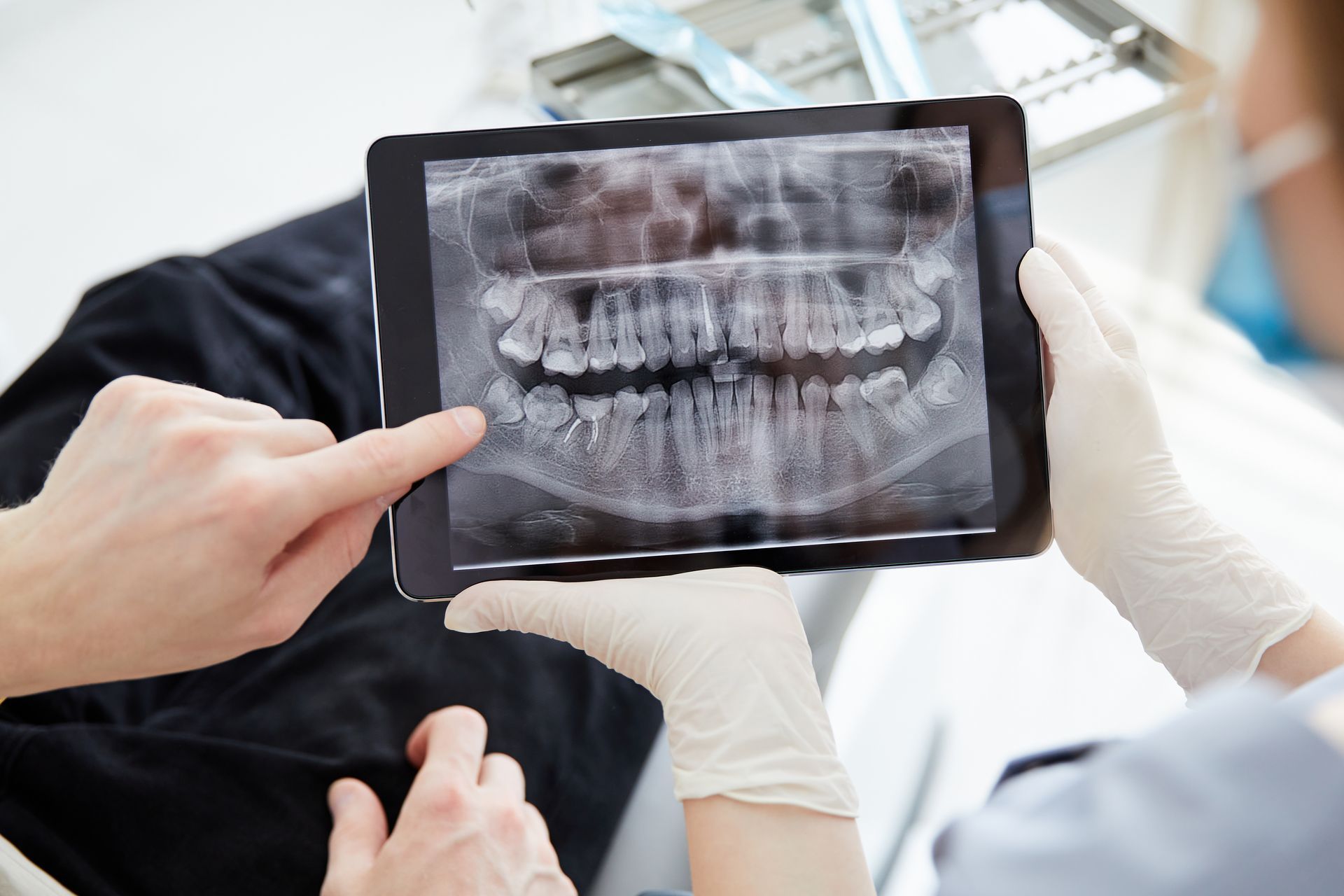 Dentist and patient examining a dental X-ray on a tablet in a clinic