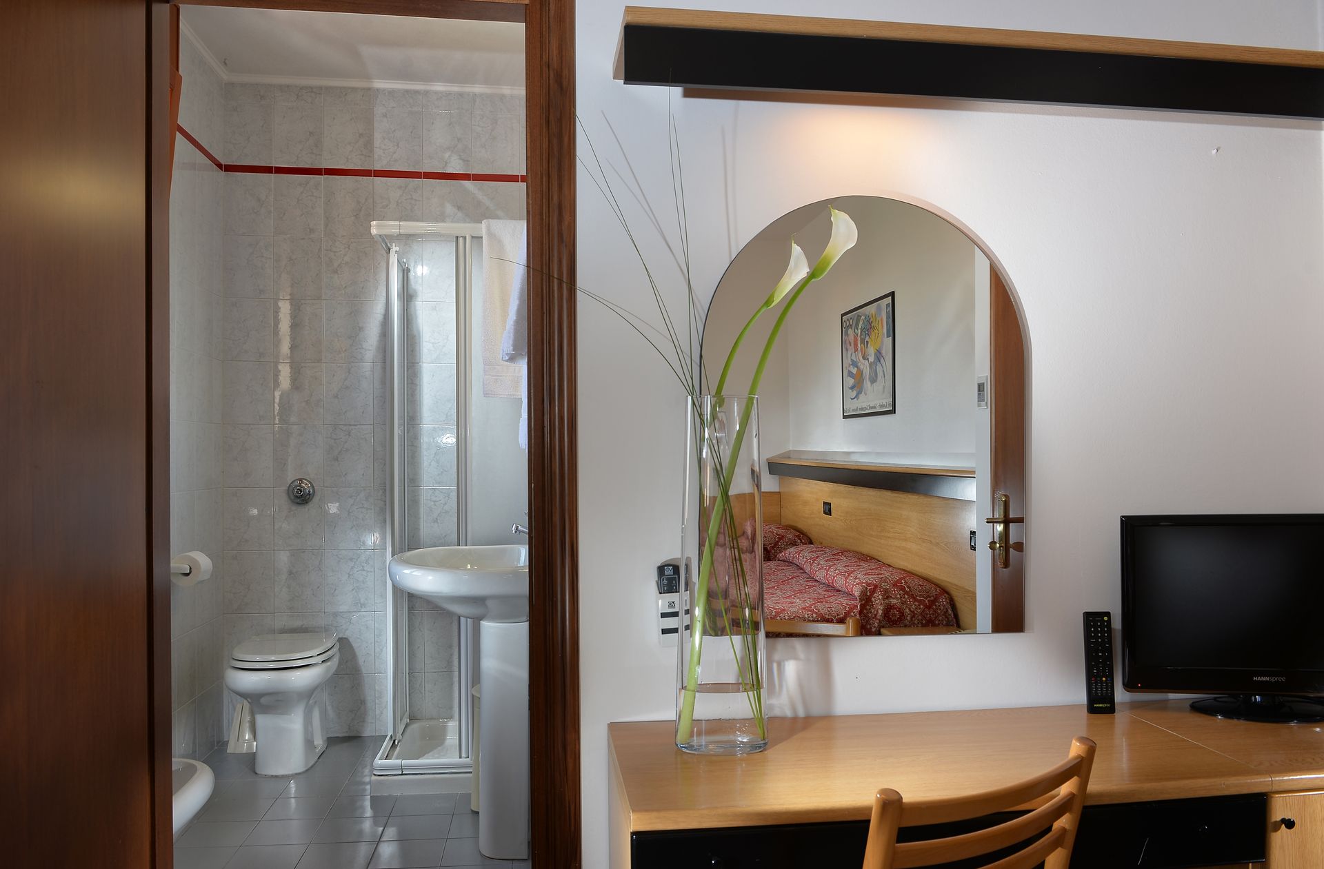 A hotel room with a desk a chair and a television