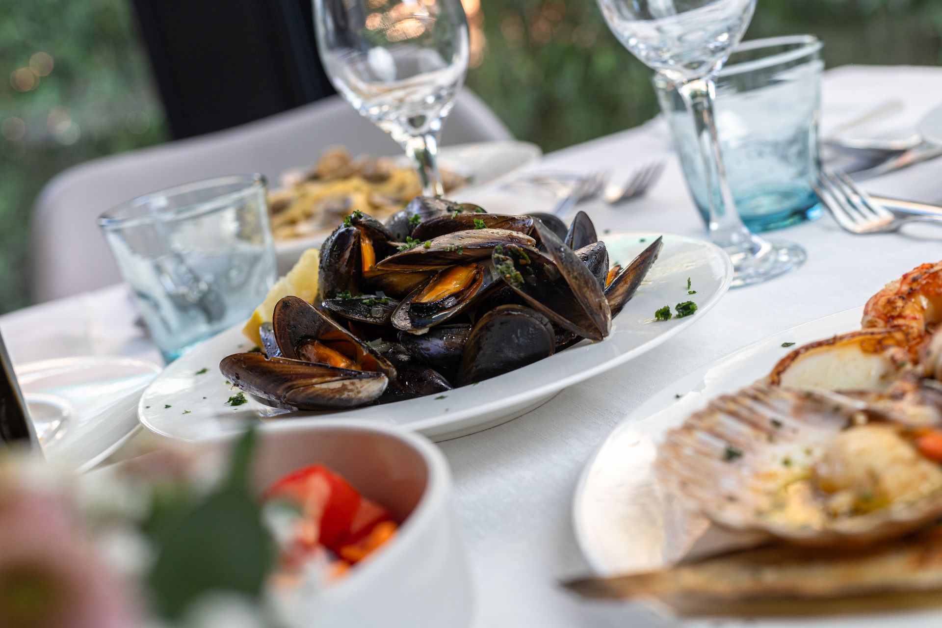 A table topped with plates of food and wine glasses.