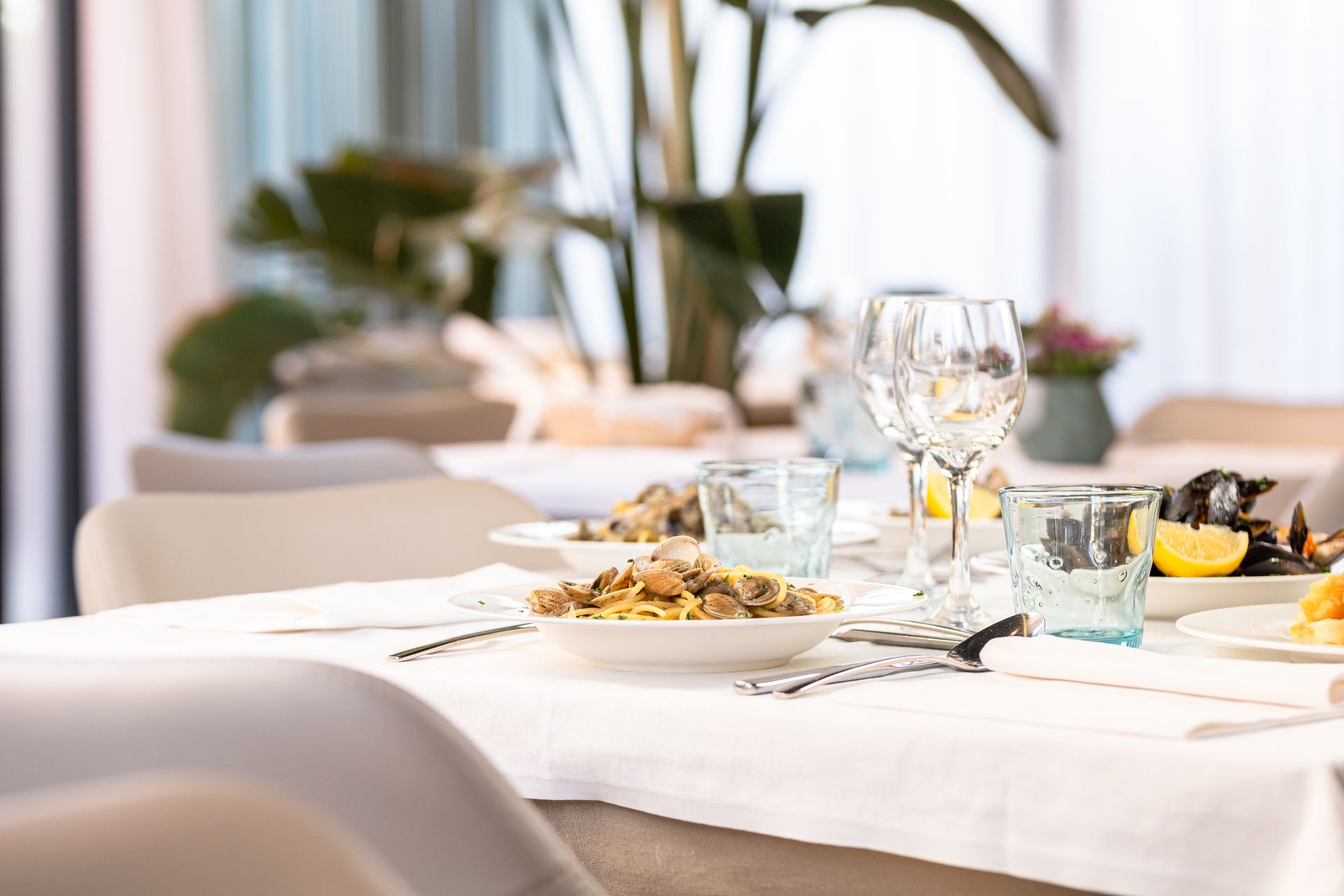 A table with plates of food and wine glasses on it in a restaurant.