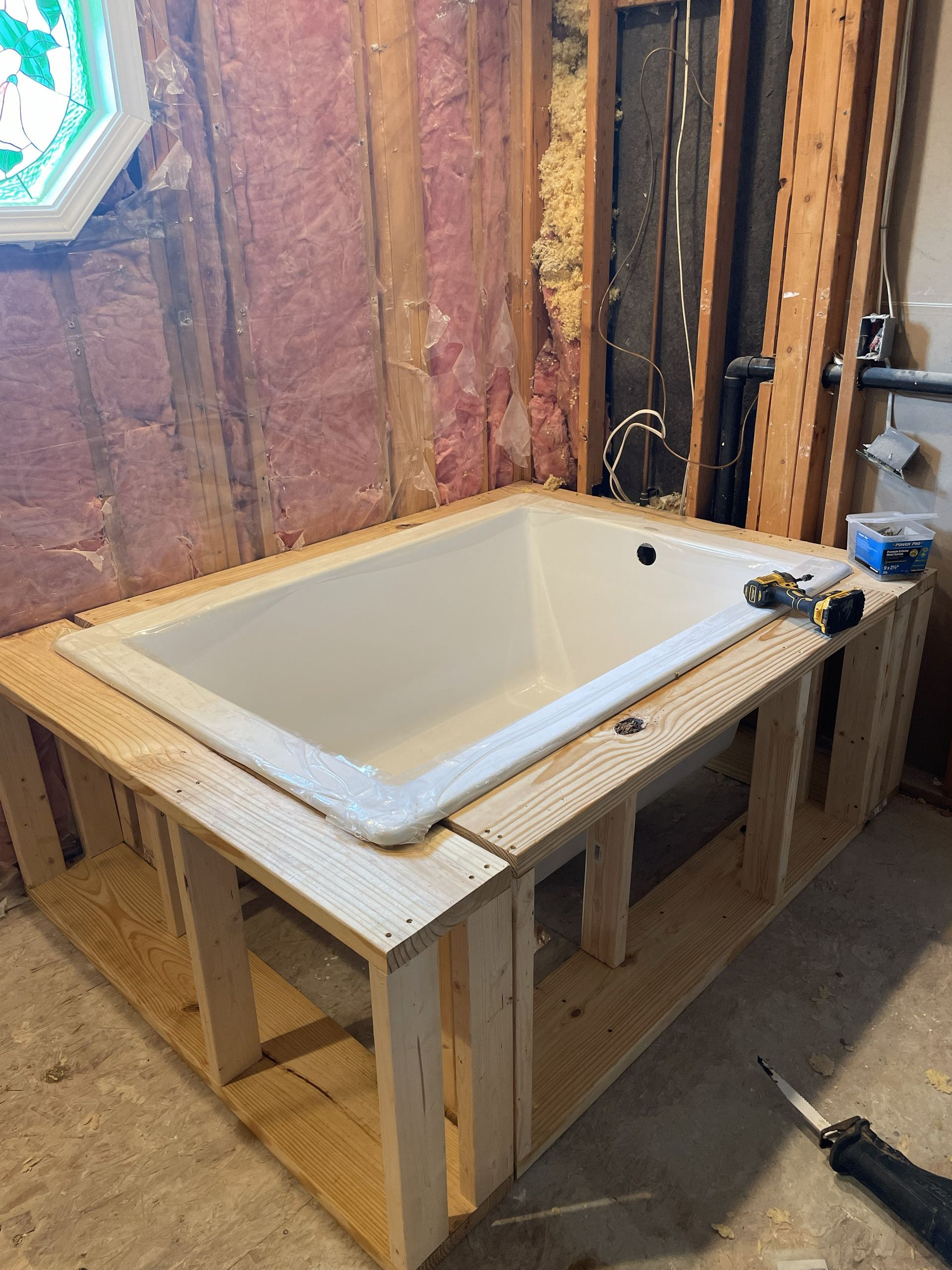 Bathroom sink mounted on a wooden frame in an unfinished room with exposed wall insulation.