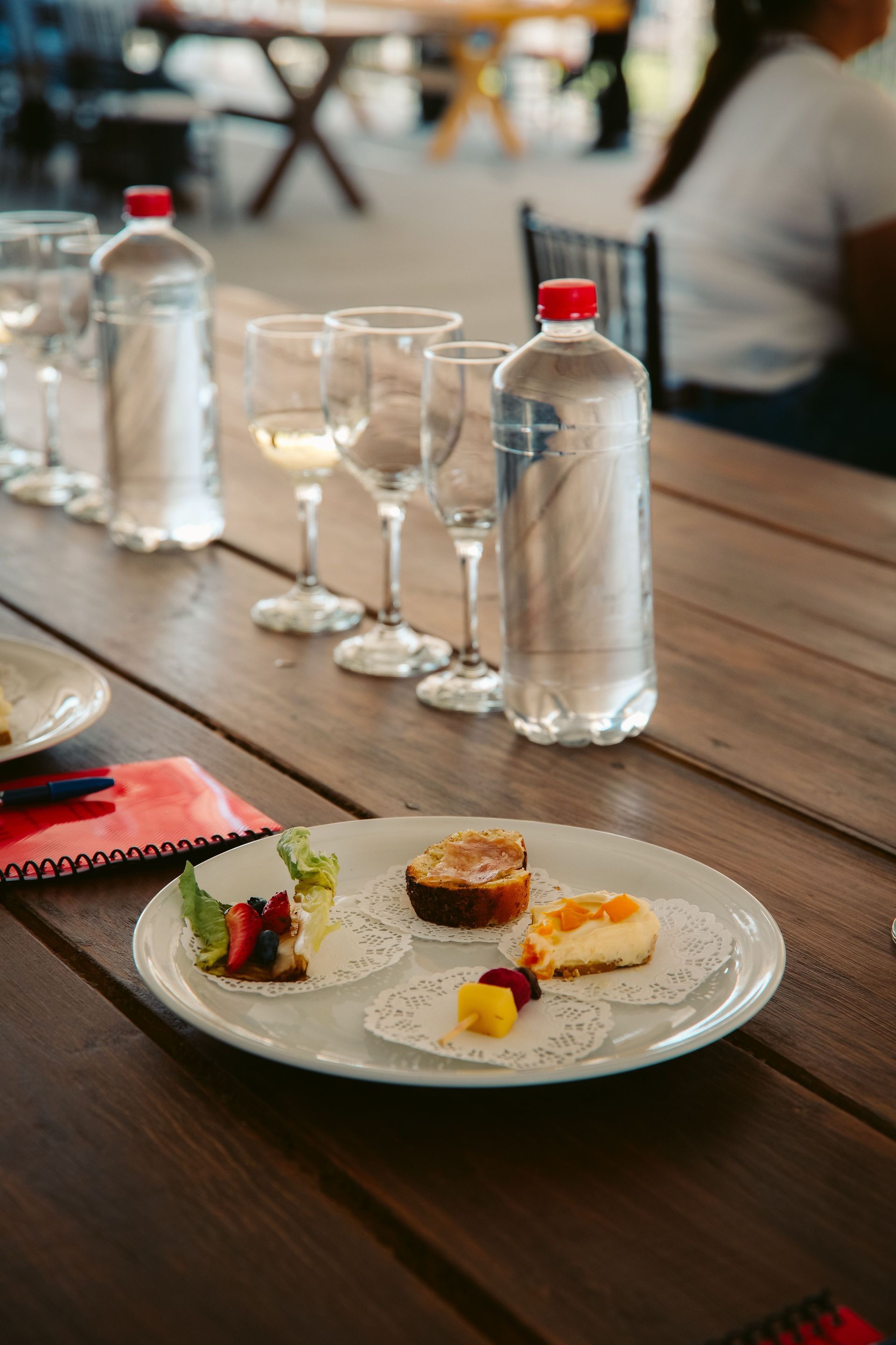 Dessert plate and bottled water on a wooden outdoor café table with glasses and napkin