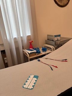 Letto ospedaliero con elettrodi medici sulla coperta e comodino con forniture ליד窗
