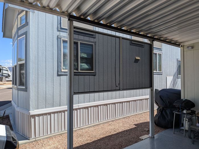 Blue mobile home with awning, gravel ground.