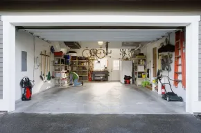 Open garage with shelves, tools, bikes, and storage along the walls