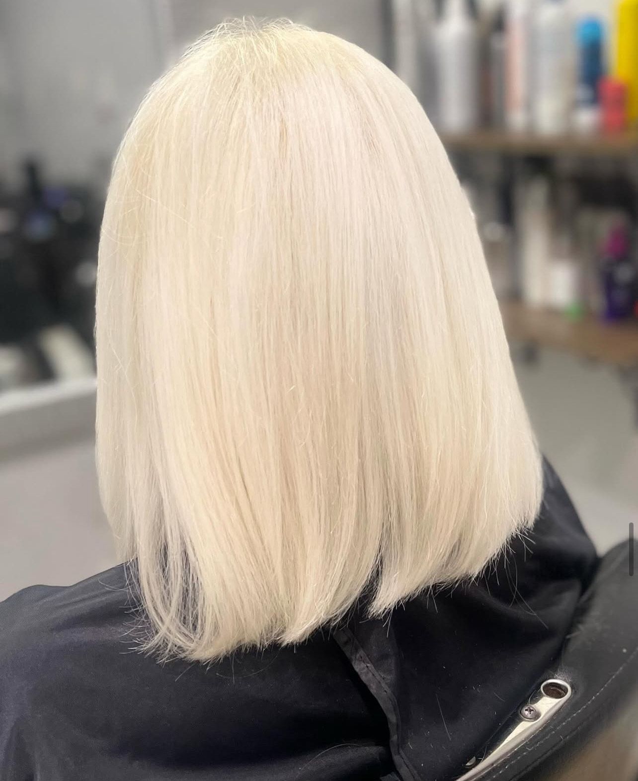 A woman with blonde hair is sitting in a chair in a salon.