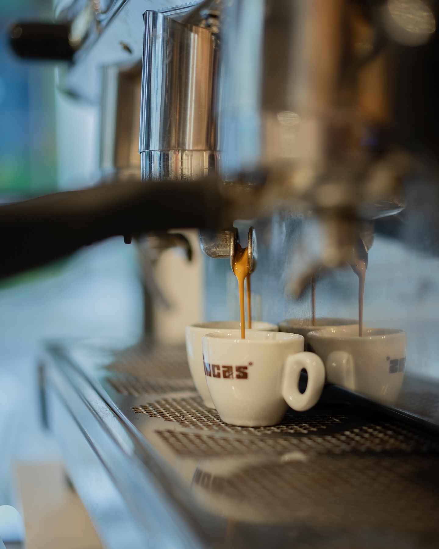 Espresso machine pouring coffee into white cups with the word 