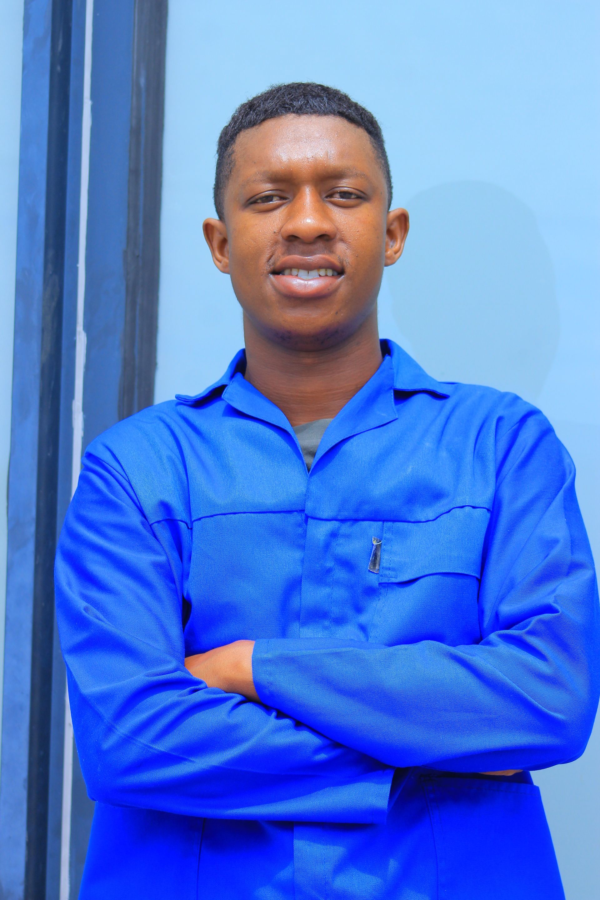 Man in blue work suit with arms crossed, smiling.