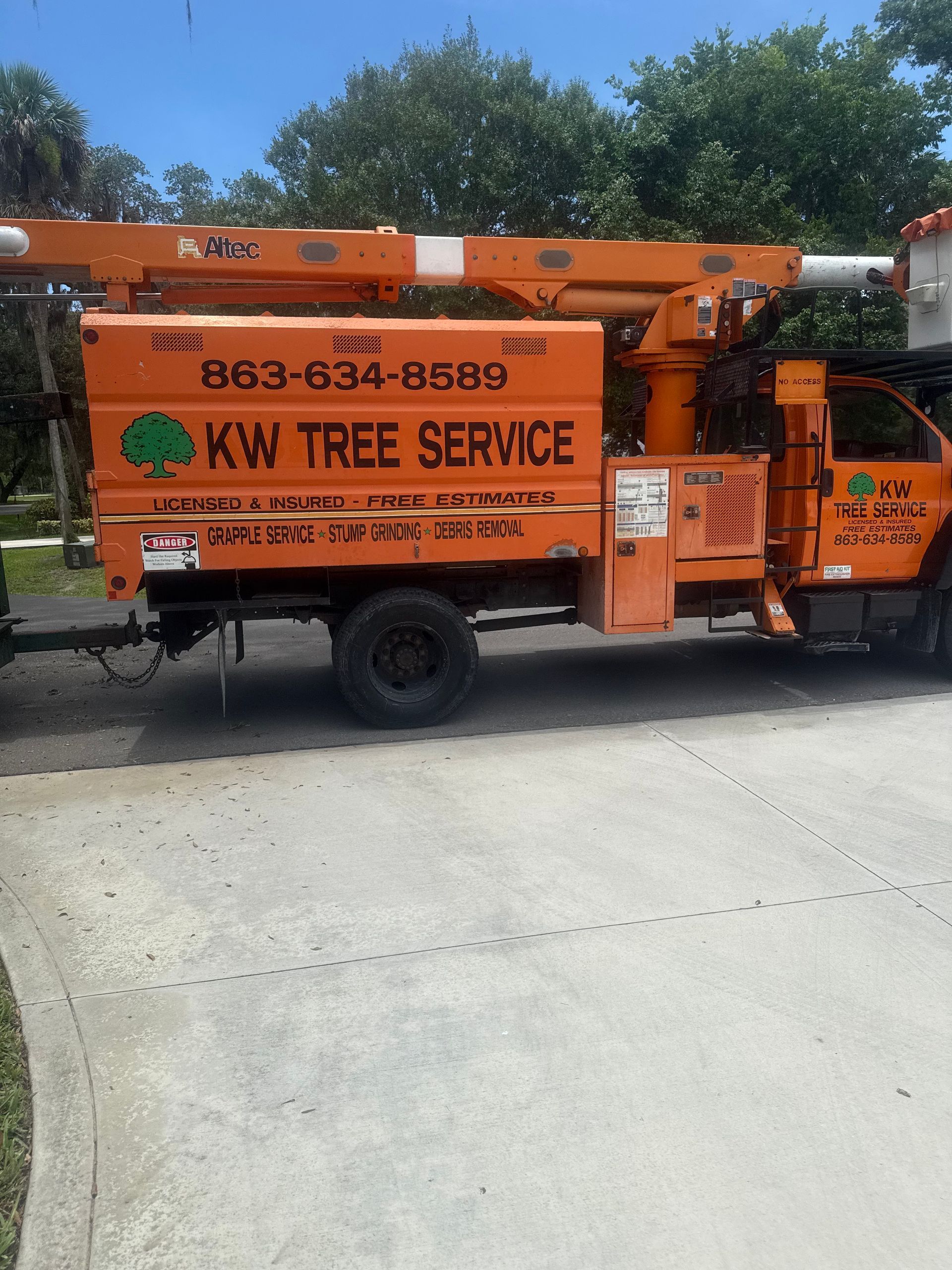 Orange KW Tree Service truck with a boom lift parked outdoors on a sunny day