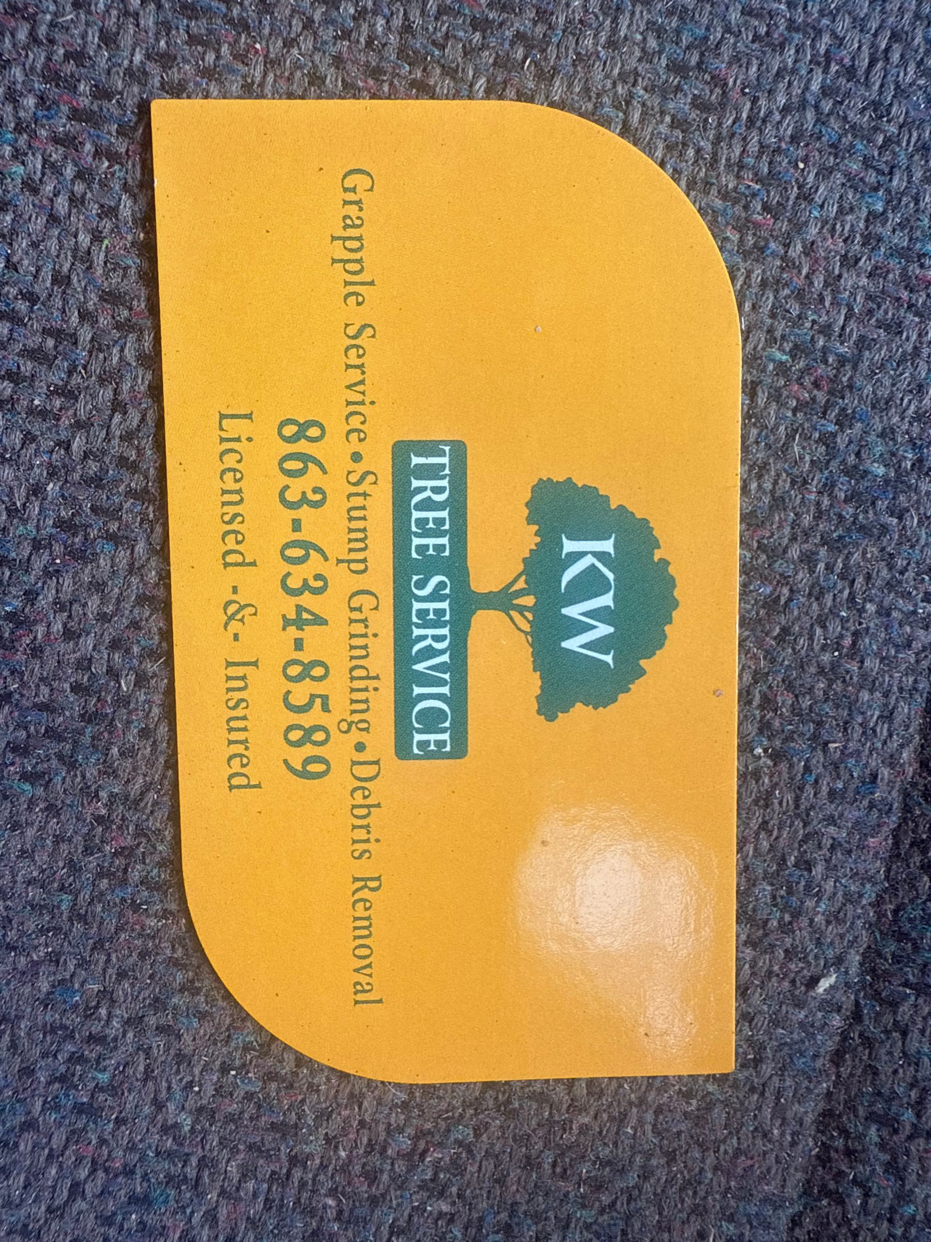 Yellow business card with teal logo and TIRE SERVICE text on a gray surface.