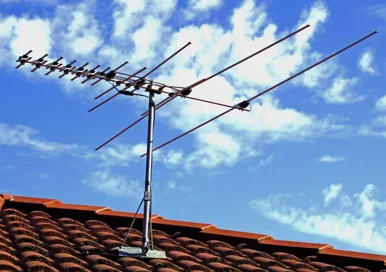 A large antenna is sitting on top of a tiled roof
