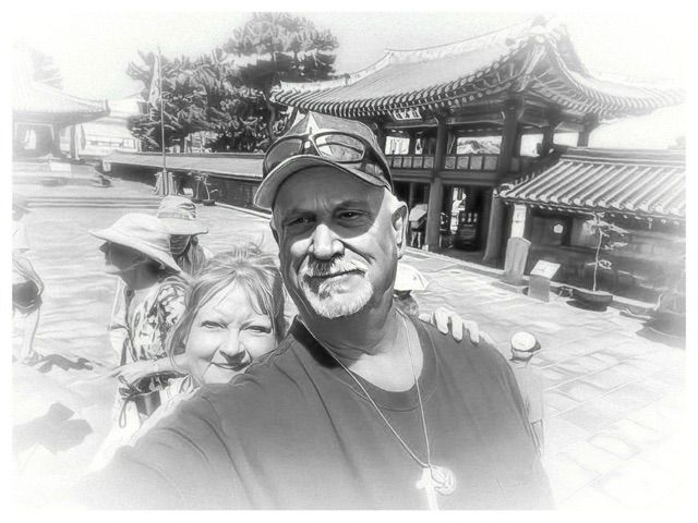 Two people taking a selfie in front of a traditional Asian temple courtyard