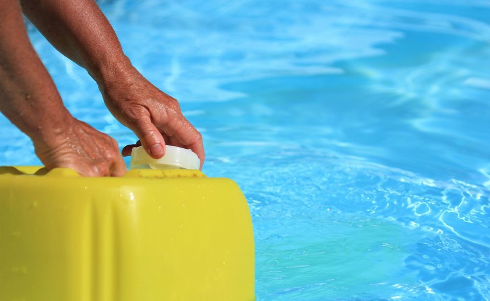 A Man Has Pouring Chlorine Over Swimming Pool — Water Equipment Service in Salamander Bay, NSW