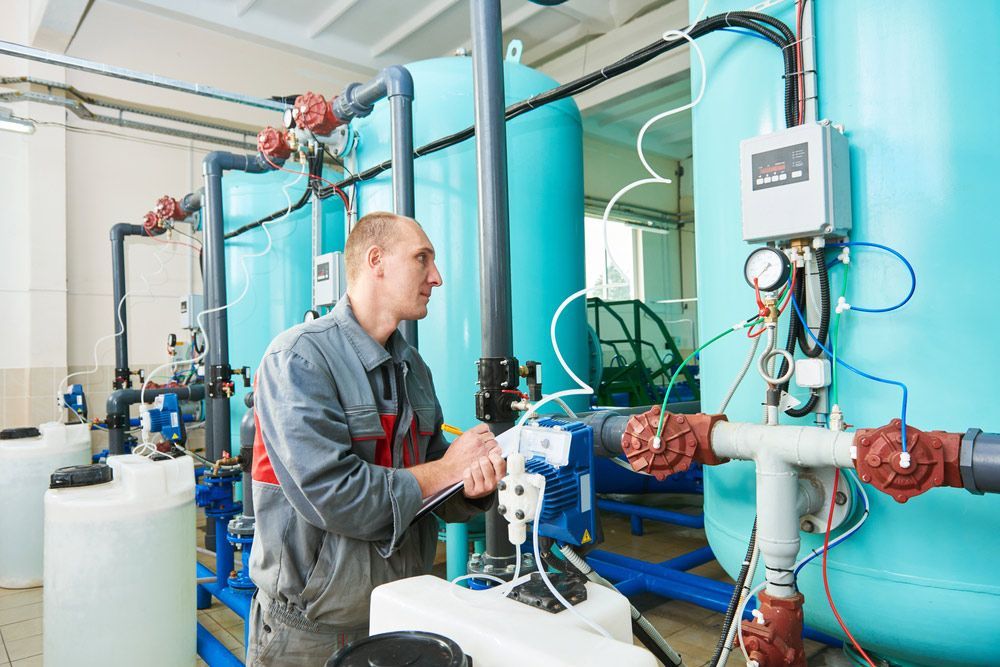 A Man Is Working With Operating Water Filtration Equipment — Water Equipment Service in Salamander Bay, NSW