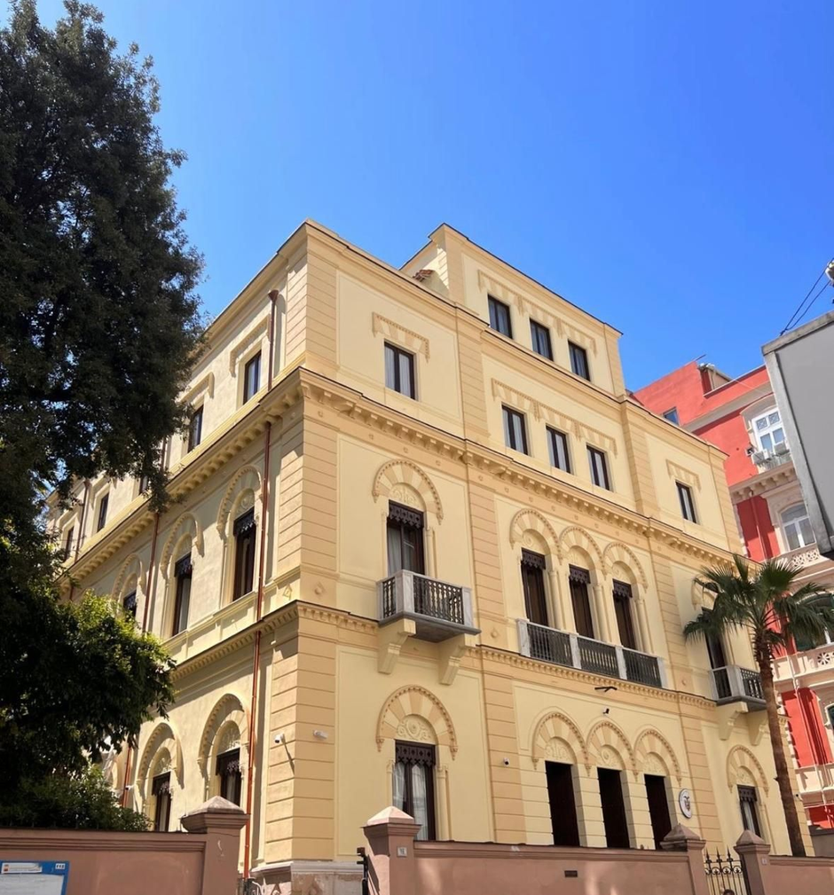 Soggiorno moderno con divano componibile beige, TV a parete, mensole e ampia finestra con tende.