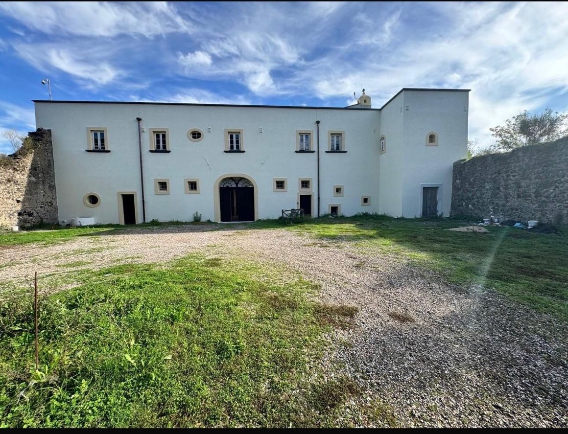 Soggiorno moderno con divano componibile beige, TV a parete, mensole e ampia finestra con tende.