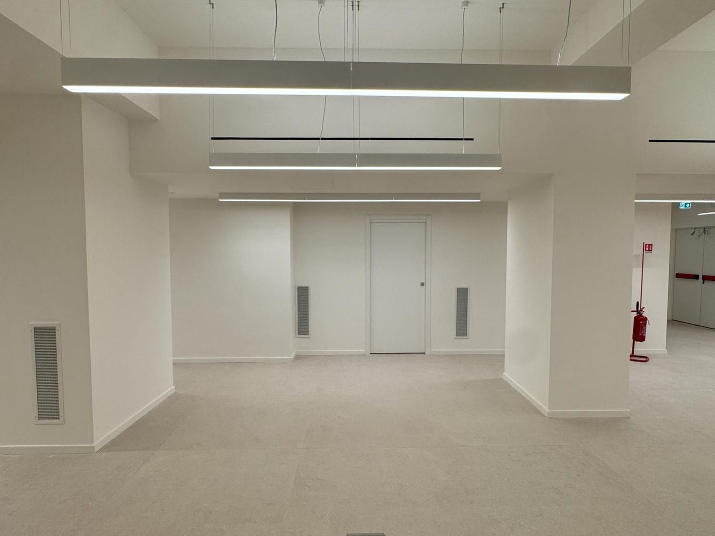 Soggiorno moderno con divano componibile beige, TV a parete, mensole e ampia finestra con tende.