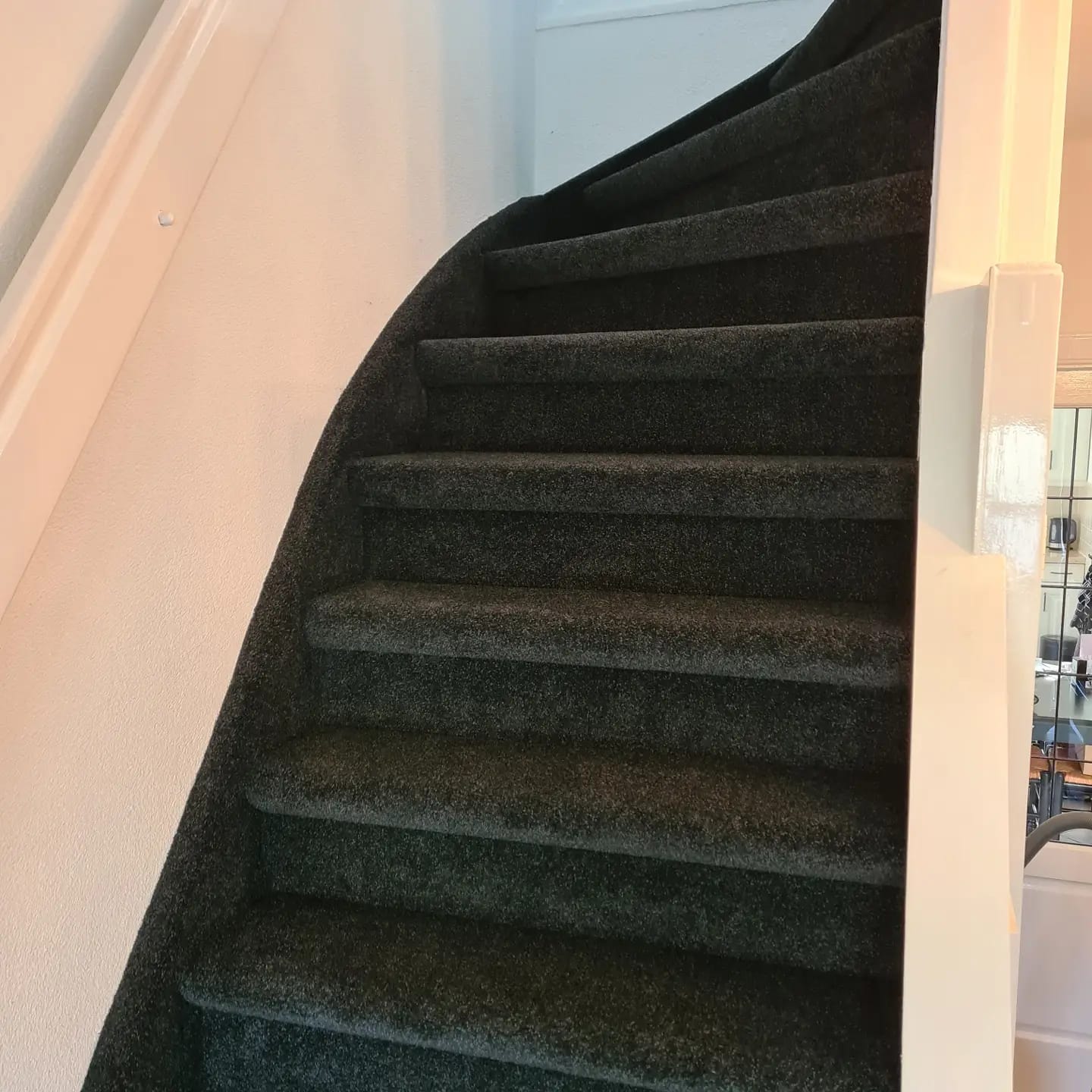 Een close-up van een trap met een witte leuning