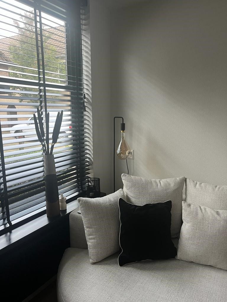 Een woonkamer met een ronde bank en een raam met jaloezieën.