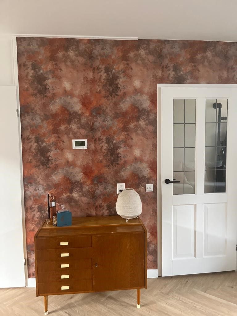 Een woonkamer met een houten ladekast en een witte deur.