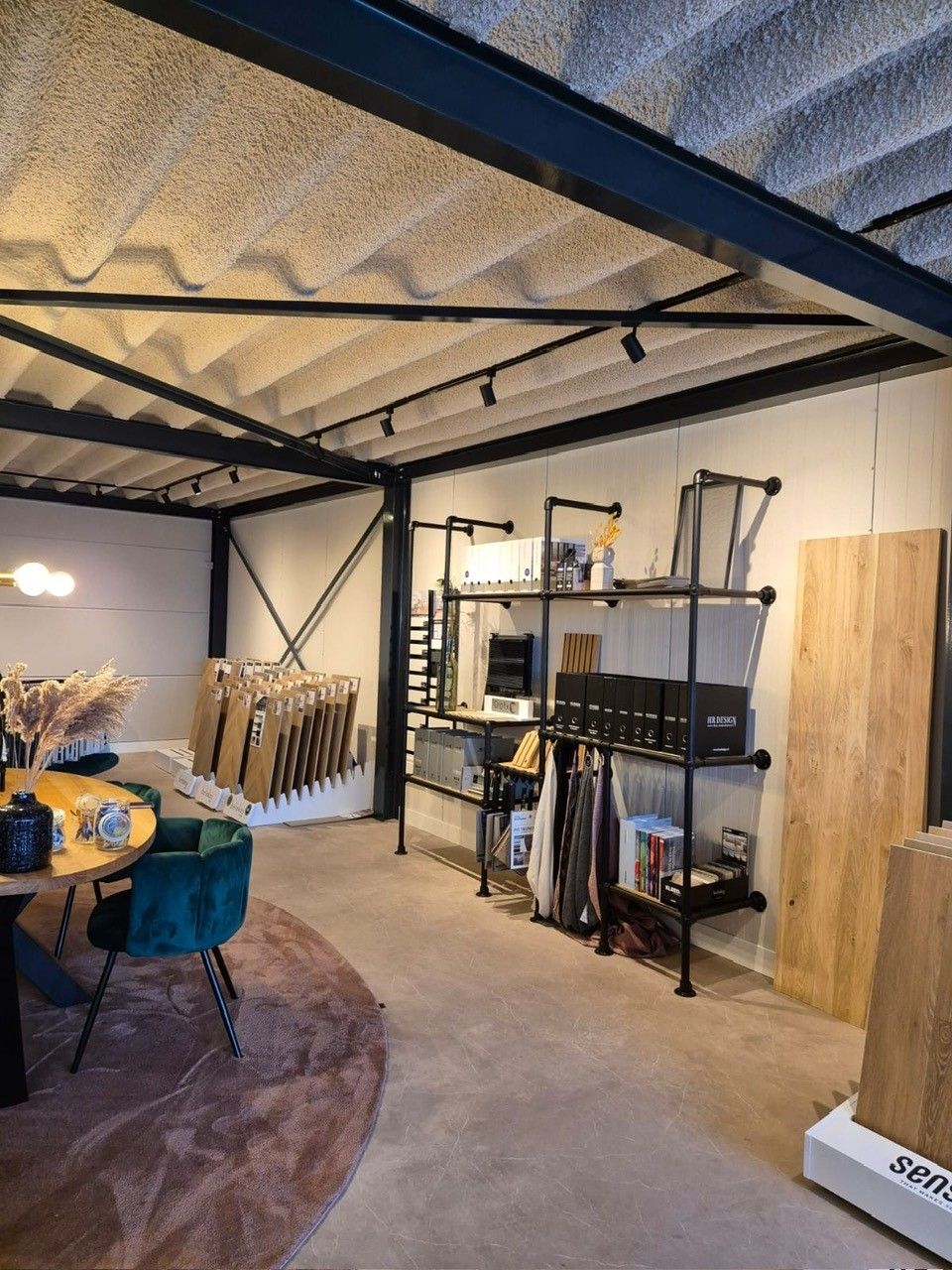 Een kamer met een tafel, stoelen, planken en een kleed.