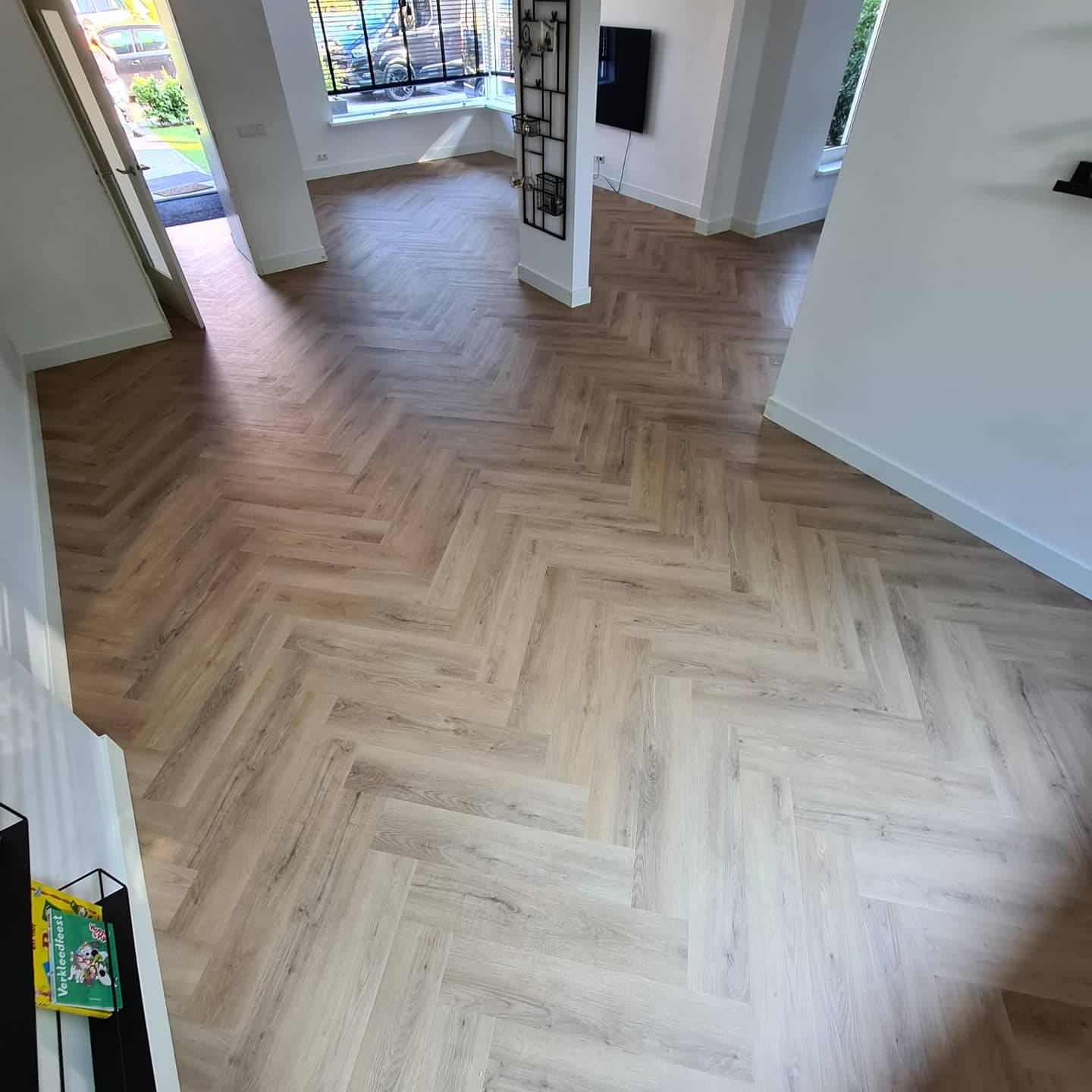 Een woonkamer met een houten vloer in visgraatmotief.
