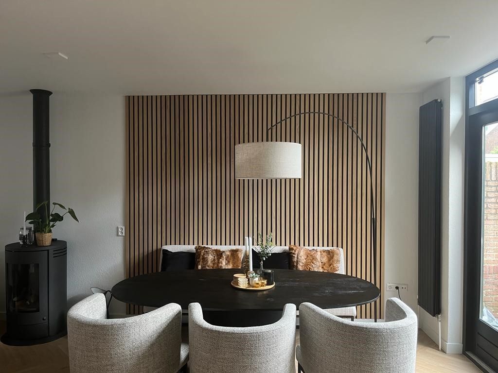 Een eetkamer met een tafel, stoelen en een gestreepte muur.