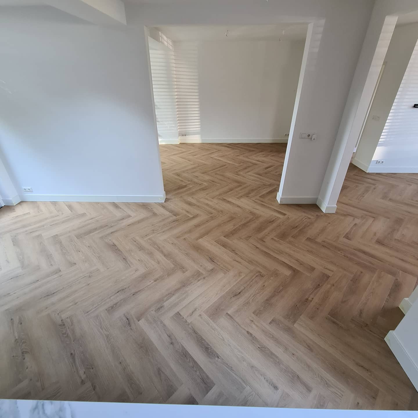 Een kamer met een houten vloer en witte muren