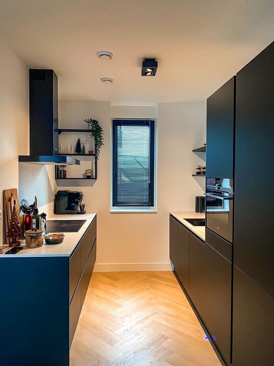 Een keuken met zwarte kasten en een houten vloer.