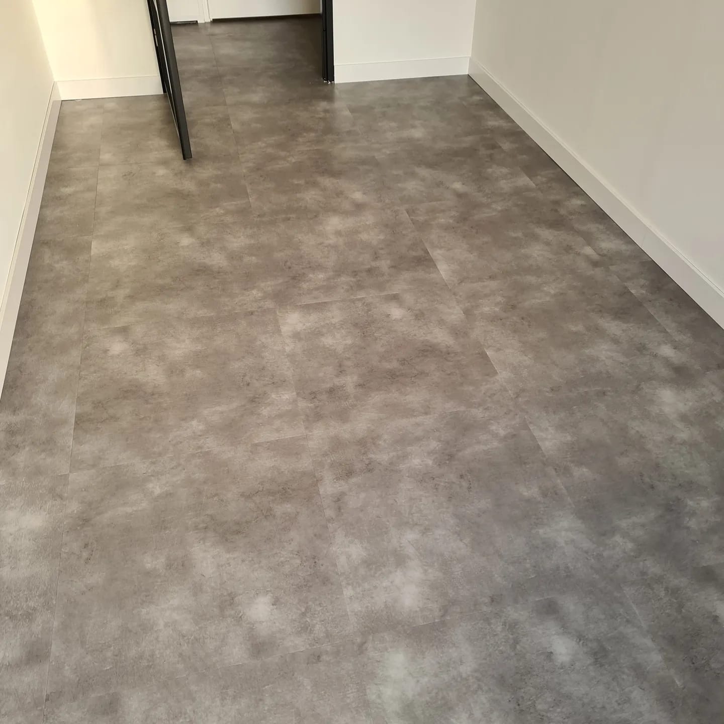 Een kamer met een trap en een grijze vloer.