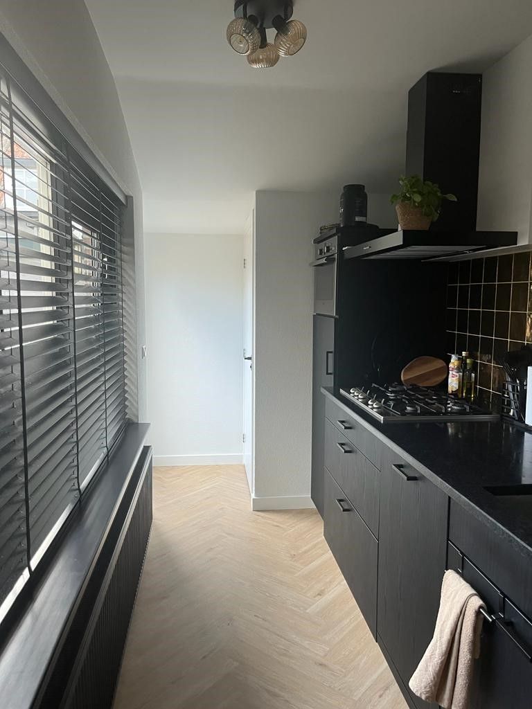 Een keuken met zwarte kasten en een kookplaat met oven.