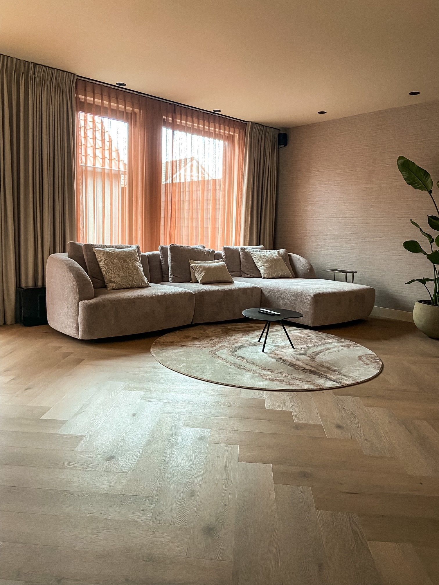Een woonkamer met een grote hoekbank en een rond kleed op de vloer.