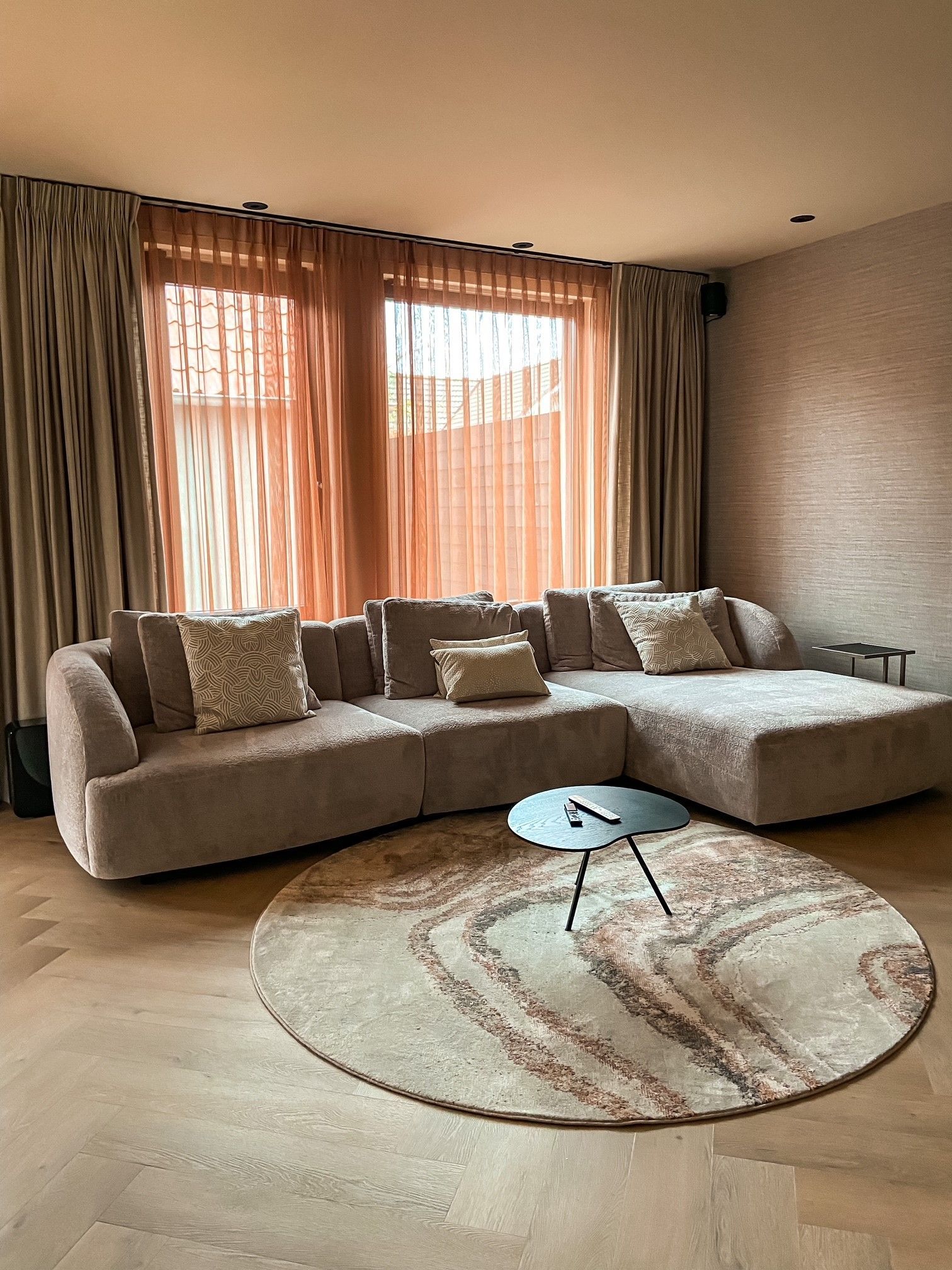 Een woonkamer met een grote hoekbank en een rond vloerkleed.