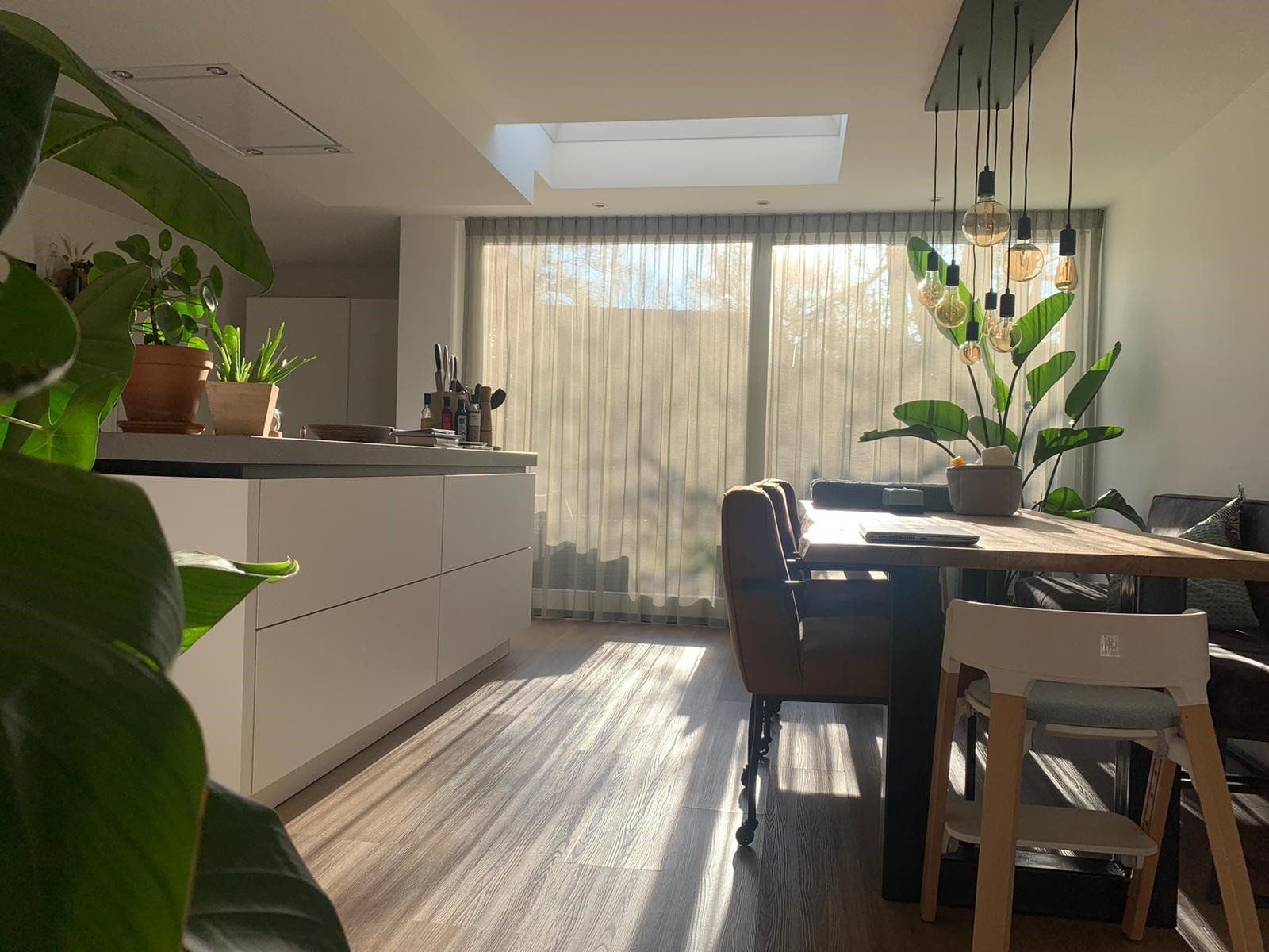 Een eetkamer met een tafel, stoelen en een dakraam.
