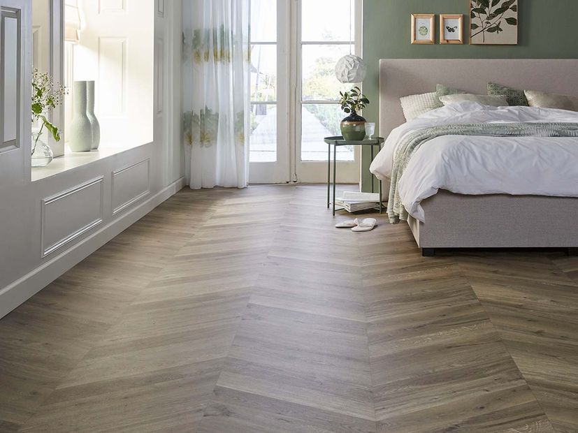 Een slaapkamer met een houten vloer en een bed.