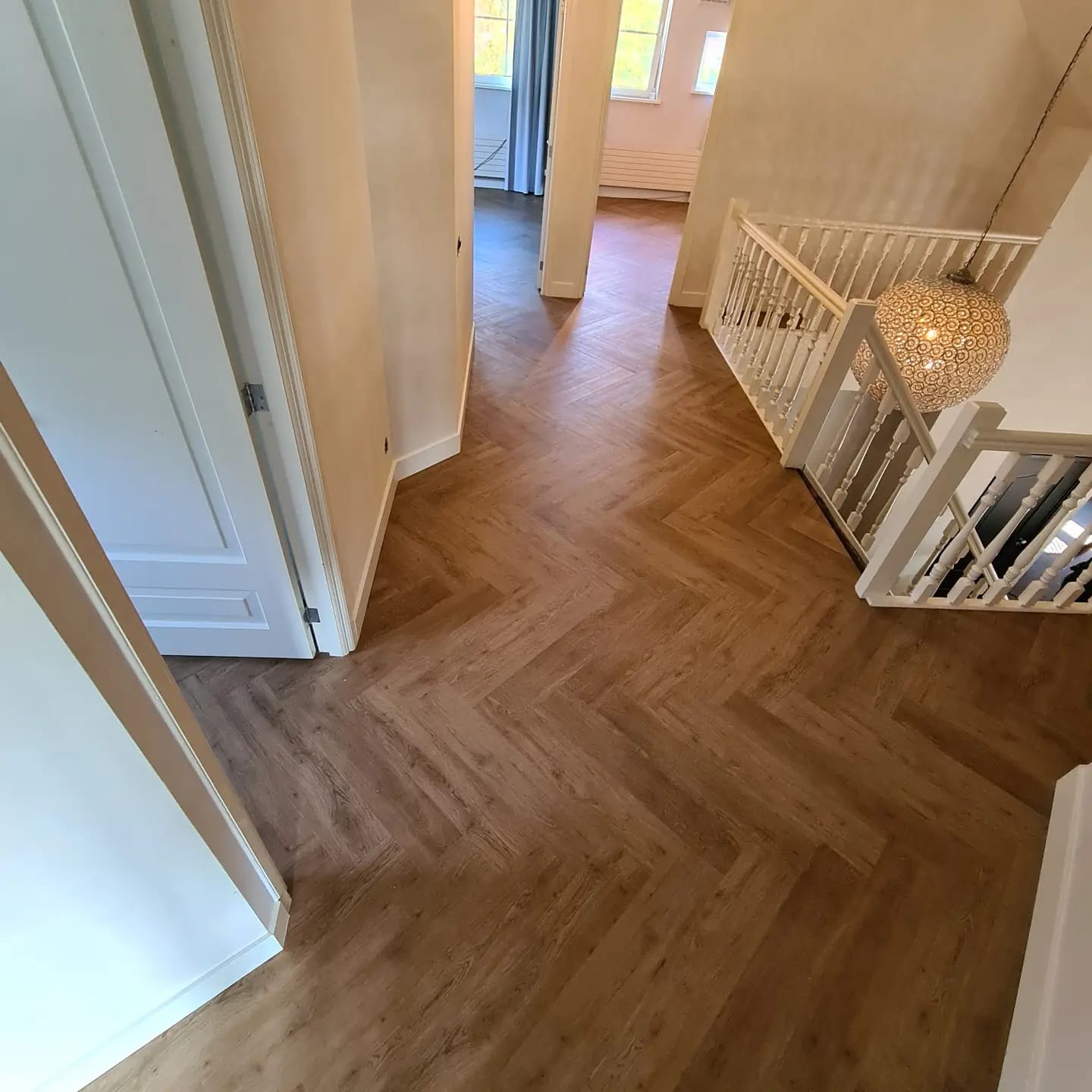 Een gang met een houten vloer en een trap