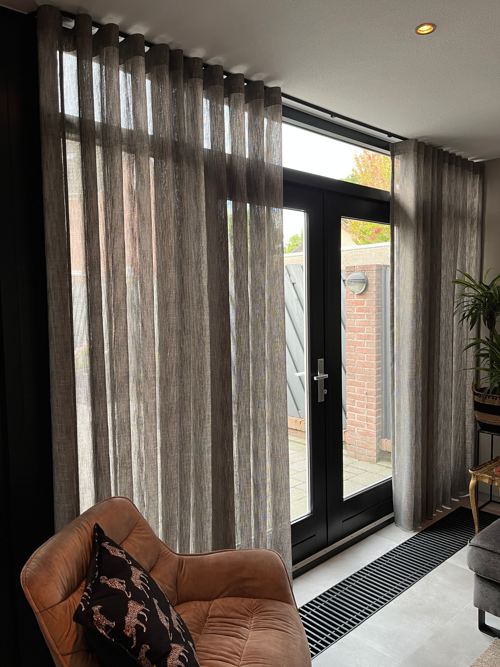 Een woonkamer met een bank, een stoel en glazen schuifdeuren.