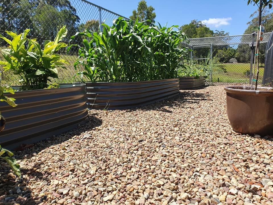 A Large White Water Tank is Sitting in the Grass in Front of a House — Foley's Tanks in Nambour, QLD