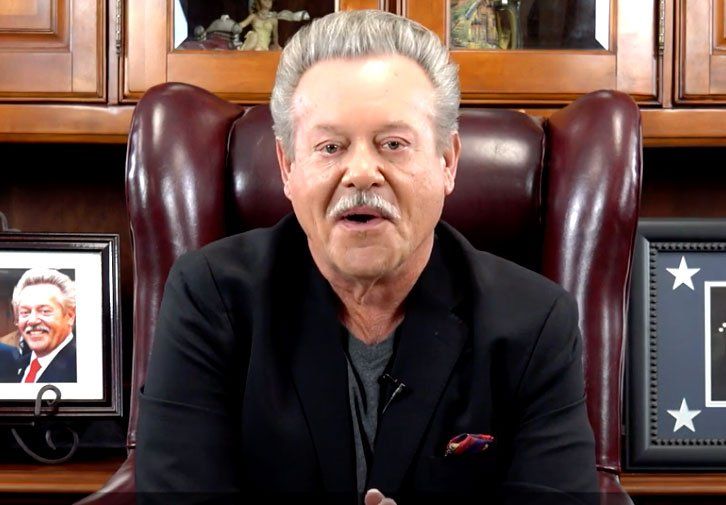 Man with graying hair, wearing a black blazer, speaking, seated in a leather chair.