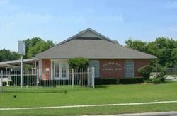 A one-story brick building with a gray roof and a sign reading