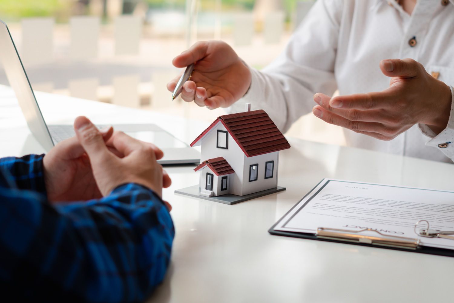 loan officer and client discussing on table with miniature house and documents