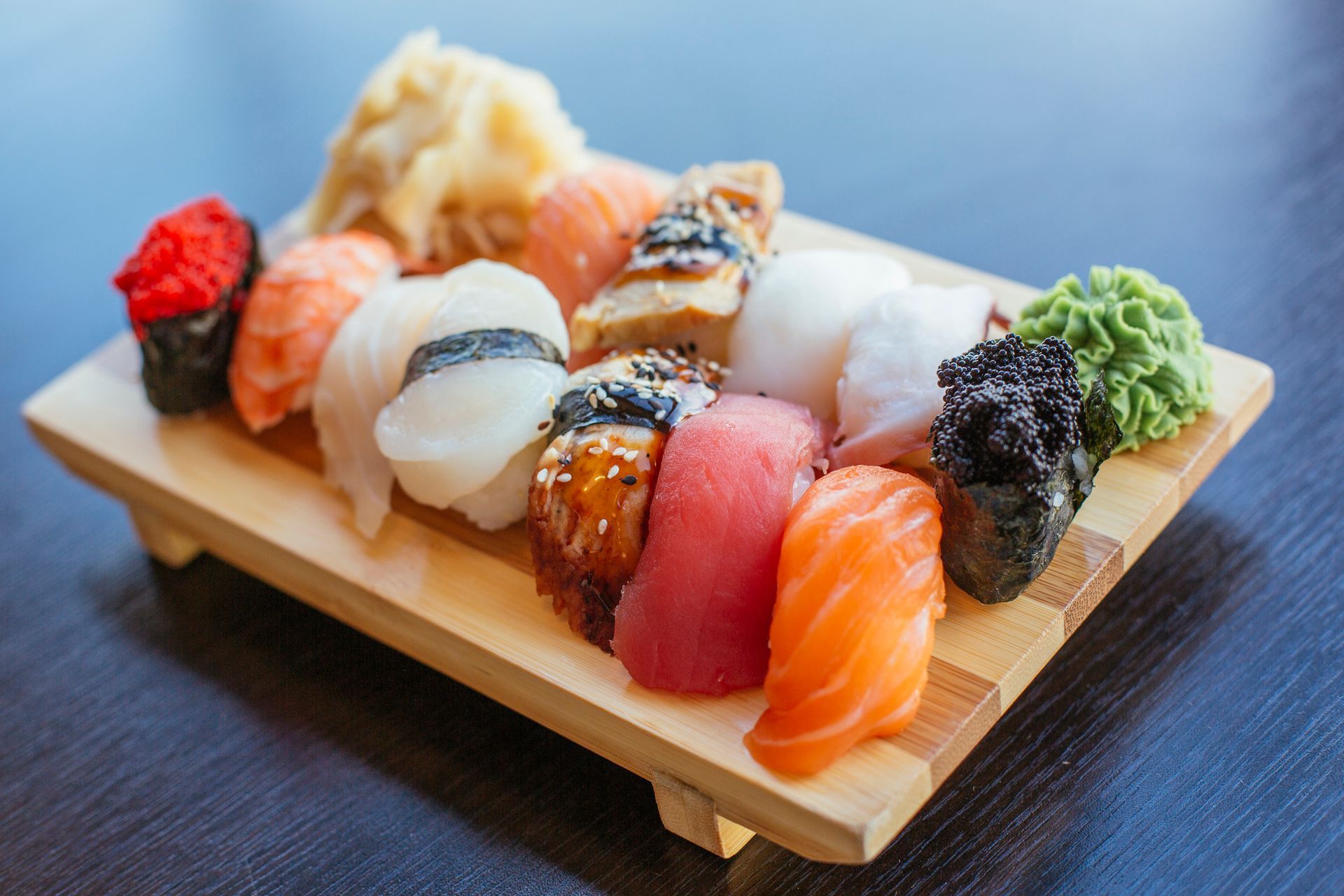 Sushi assortito su un tagliere di legno, tra cui nigiri con salmone, tonno e frutti di mare.