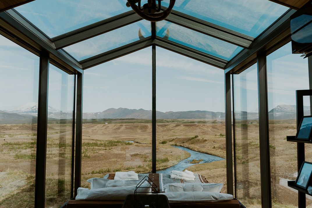 A room with a lot of windows and a view of a iceland river.