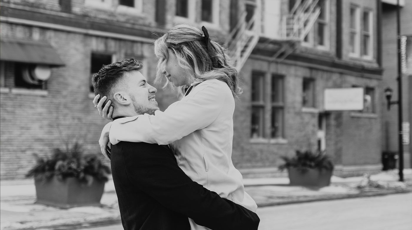 A man is carrying a woman on his shoulders in a black and white photo.