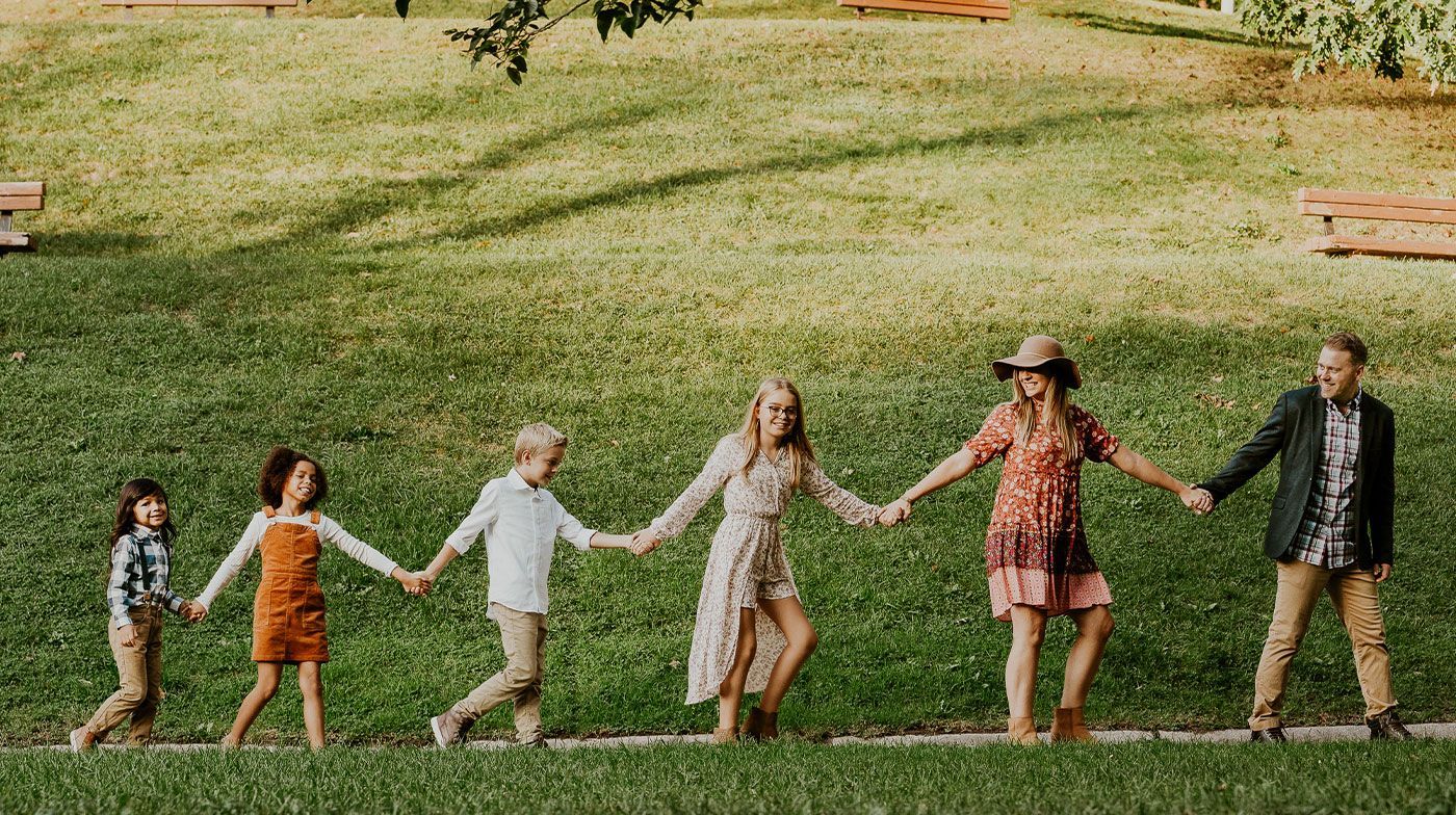 A family is holding hands while walking in a park.