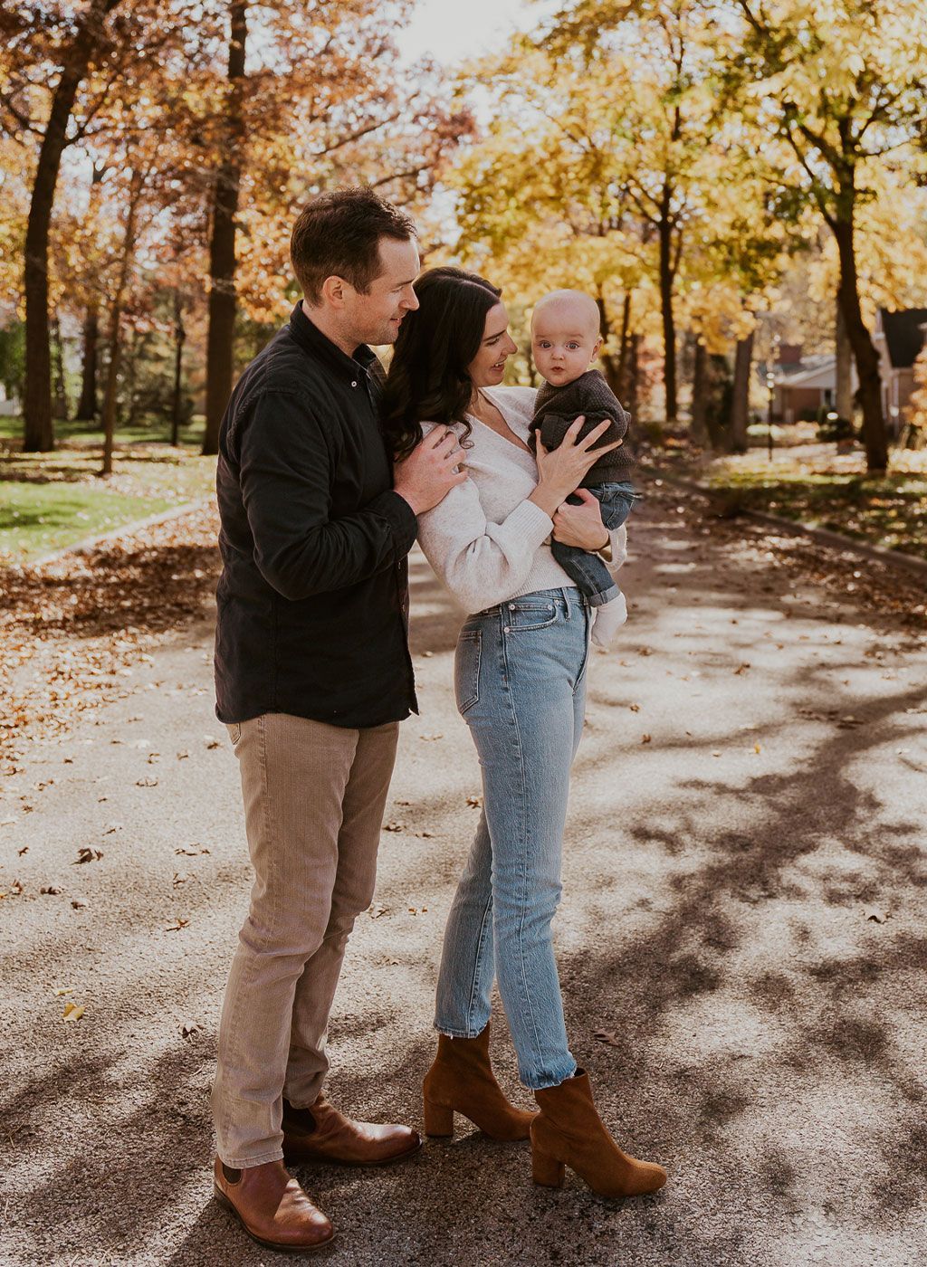 A man and woman are holding a baby in a park.