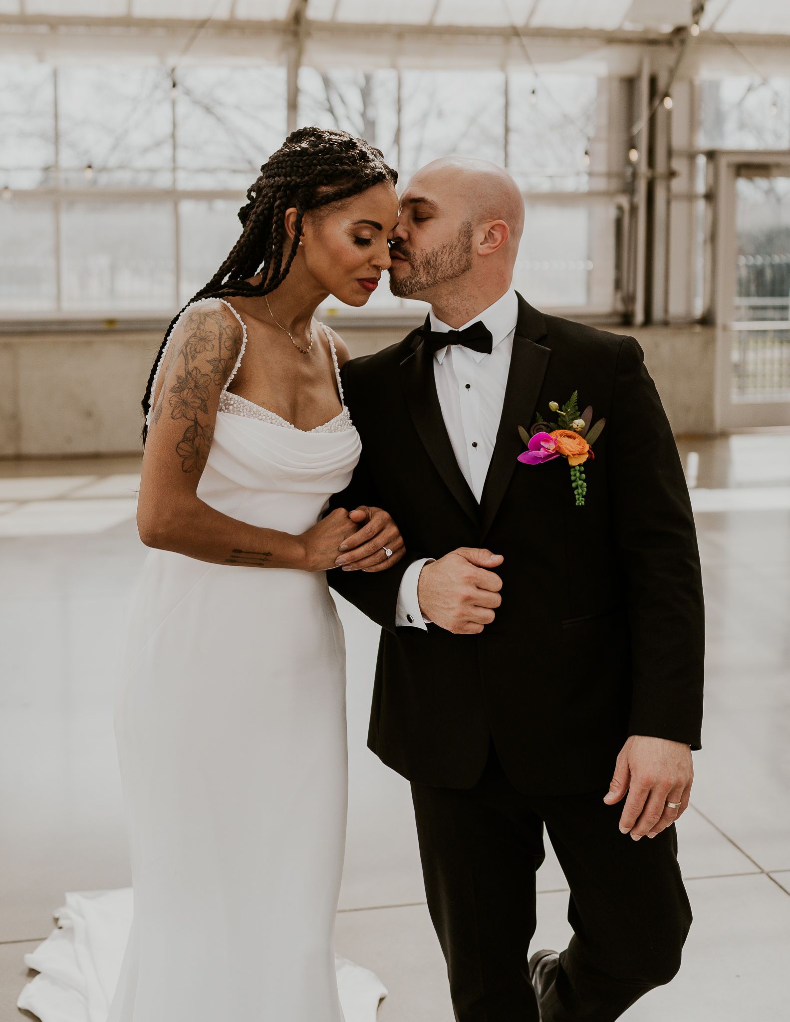 Bride and groom holding hands outdoors, smiling at each other in wedding attire