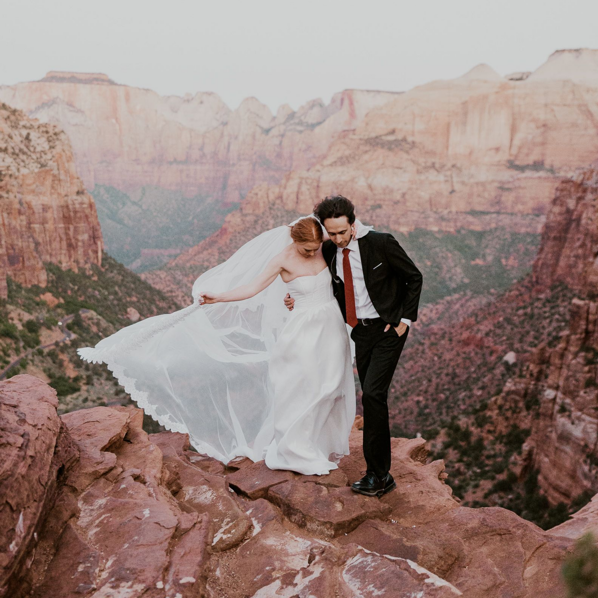 A bride and groom are sitting on the deck of a sailboat.