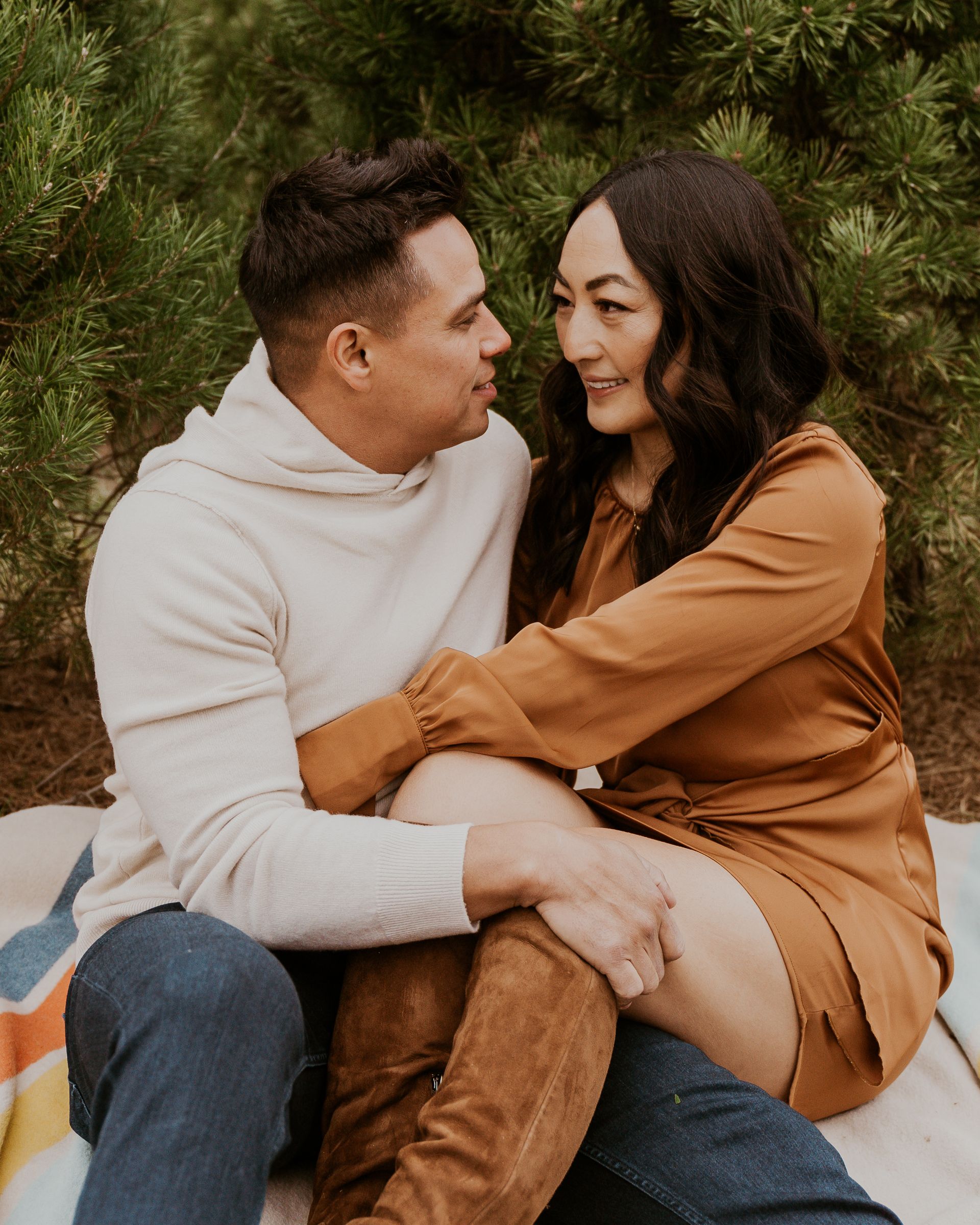 A man and a woman are sitting on a blanket and looking at each other.